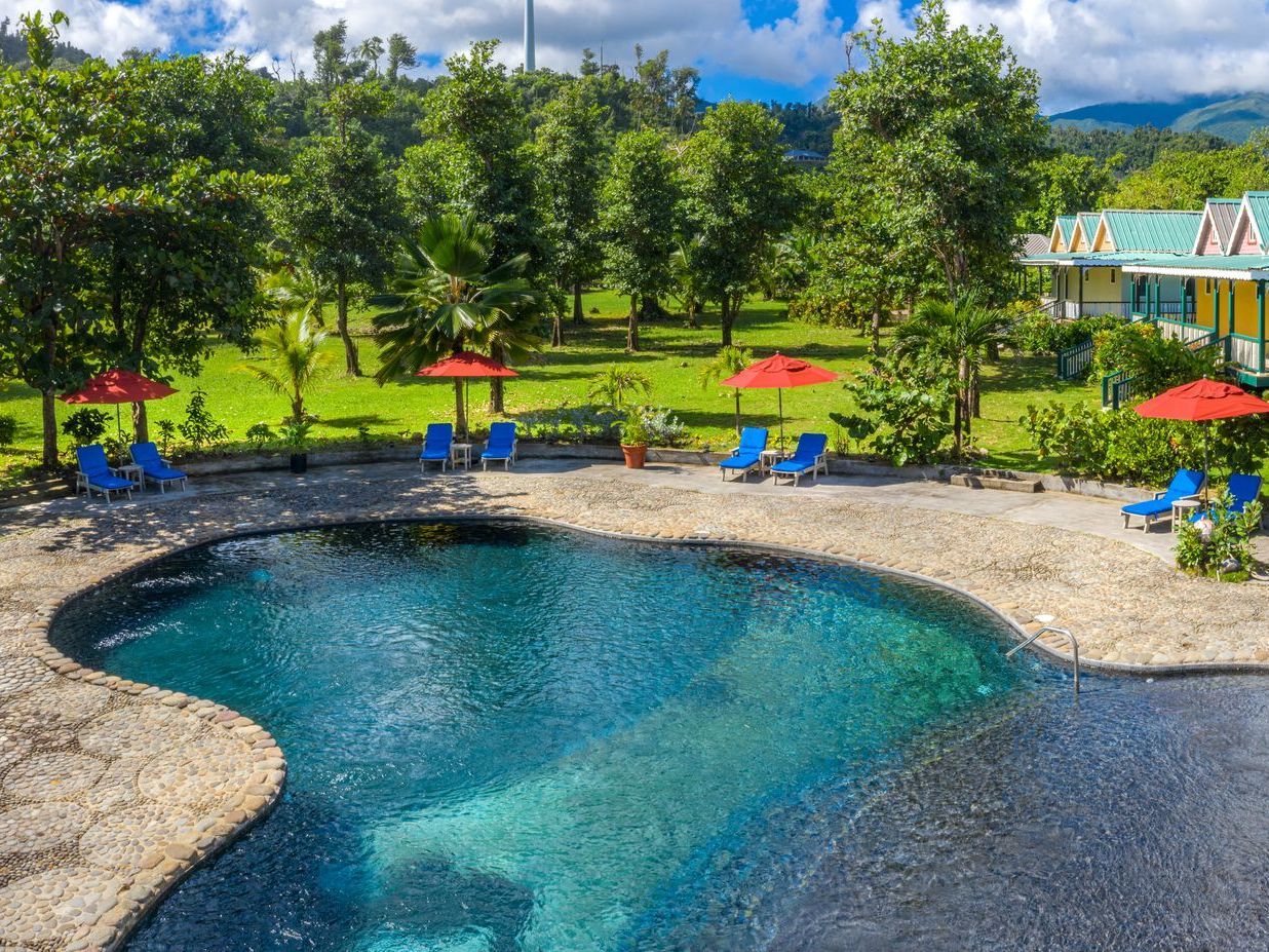 Rosalie Bay’s freshwater swimming pool framed by palms, loungers and tropical gardens